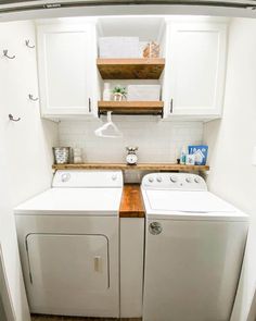 a washer and dryer in a small room with white cabinets on the wall