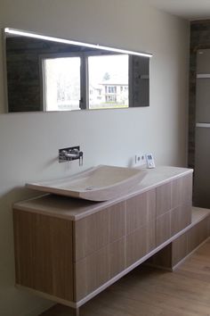 a bathroom with a sink, mirror and wooden cabinet in it's center area