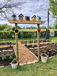 an outdoor garden with wooden posts and birdhouses on the top, surrounded by plants