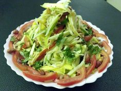 a salad with lettuce and tomatoes in a white bowl on a black table