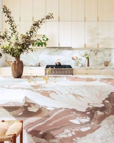 a kitchen with marble counter tops and wooden stools in front of an island that has flowers on it