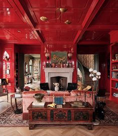 a living room with red painted walls and furniture in the center, along with bookshelves