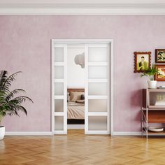 an empty room with pink walls and wooden floors, potted plant in the corner