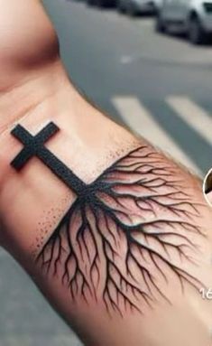 a person with a cross and tree roots tattoo on their arm, next to a street