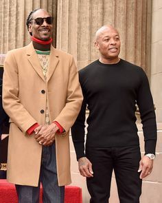 two men standing next to each other on a red carpet