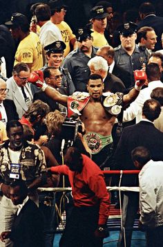 a crowd of people standing around each other with boxing gloves on their shoulders and hands in the air