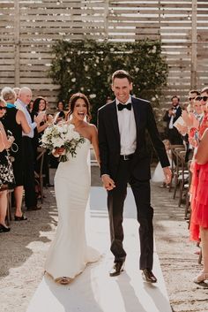 a bride and groom walking down the aisle after their wedding ceremony with guests in the background