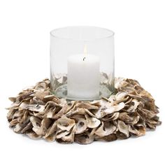 a candle sitting on top of a glass bowl filled with shells