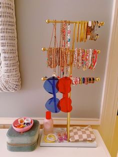 a jewelry rack with bracelets and rings on it sitting on a table next to a purse