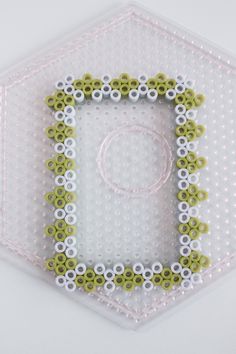 an object made out of legos and beads on a white surface with a hexagonal pattern