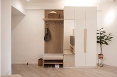 a living room with white walls and wooden flooring next to a large open closet