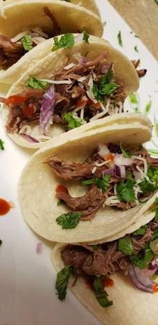 three tacos with meat, onions and cilantro on a plate