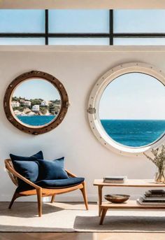 a living room with two round windows overlooking the ocean