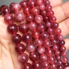 a hand holding some red beads in it's palm