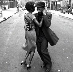 a man and woman dancing on the street in an old black and white photo,