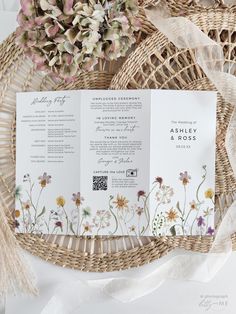 an open wedding program sitting on top of a wicker basket next to some flowers