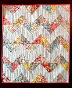 a close up of a quilt on a wooden table with a red frame around it