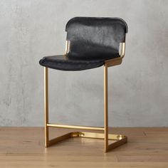 a black leather bar stool with gold legs