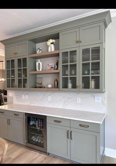 a kitchen with gray cabinets and marble counter tops