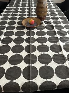 a table topped with a vase filled with an orange next to a black and white polka dot table cloth