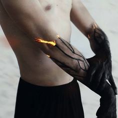 a man wearing black gloves with flames on his arm and hands, holding something in the other hand