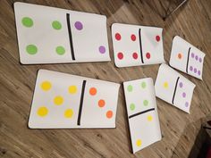 four pieces of paper with different colored dots on them sitting on a wooden floor next to a red chair