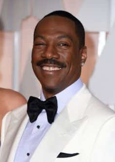 a man in a tuxedo smiles at the camera