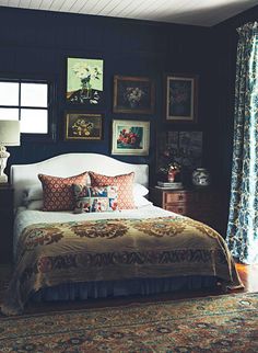 a bed sitting in a bedroom next to a window filled with pictures on the wall