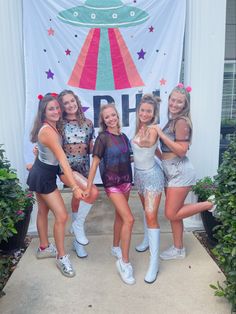 four girls posing in front of a sign