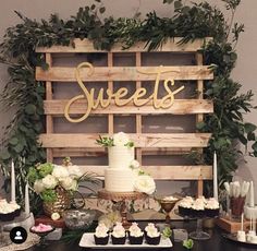 a table topped with cake and cupcakes next to a wooden sign that says sweets