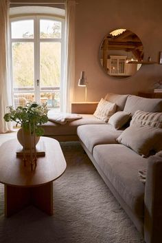 a living room filled with furniture and a round mirror on the wall over a window