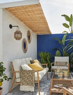 an outdoor living area with wicker furniture and potted plants on the side wall