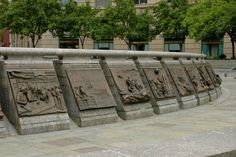 a stone wall with carvings on it and trees in the background