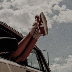 a woman's legs sticking out of the window of a car while wearing tennis shoes