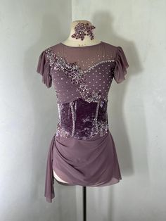 a mannequin wearing a purple dress with sequins on the bust and shoulders