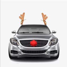 a silver car with reindeer antlers on its head and red ball in the front