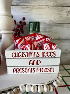 christmas trees and presents placed in a white box on a table with red ribbon around it