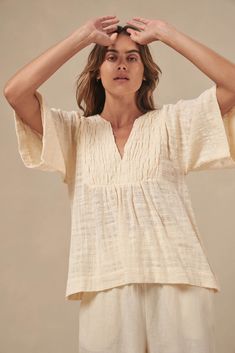 The Tulum top from Australian brand Little Lies is a perfect staple for spring/summer. Features pleated detail on the front, a flattering square sleeve and a v-neckline. This gorgeous top is an oversized fit that can be paired with your favorite pants or shorts. Semi-sheer. Materials: 100% Cotton Care: Wash with like colors; cold gentle machine wash; do not bleach; lay flat to dry; warm iron; do not tumble dry. Size Info: Model is 5'8" and is wearing a size S; relaxed fit Size Guide | Shipping Policy Casual Short Sleeve V-neck Top For Brunch, Versatile V-neck Blouse For Beach, Relaxed V-neck Blouse For Day Out, Versatile Beige V-neck Blouse, Spring Top With Notched Neckline For Day Out, Beige V-neck Summer Top, Effortless V-neck Blouse For Day Out, Beige V-neck Top For Summer, Chic Split Neck Top For Day Out