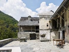 an old stone building sitting on top of a hill next to a wooden table and chair