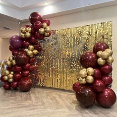 some red and gold balloons are in front of a large piece of art that is on the floor