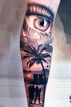 an eye and palm tree tattoo on the right leg with two people looking at it