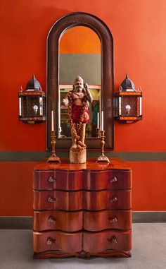 an old dresser with a mirror and statue on it