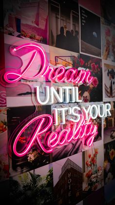 the words dream until it's your reality are lit up against a wall covered in photos