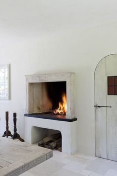 a fireplace in a room with white walls and tile flooring that has a door open to the fire place