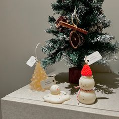 a small christmas tree with two snowmen next to it on top of a table