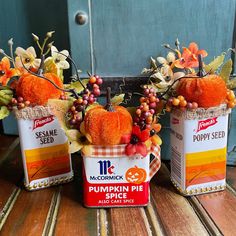 three small pumpkins are sitting in tins