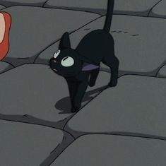 a black cat walking across a stone floor