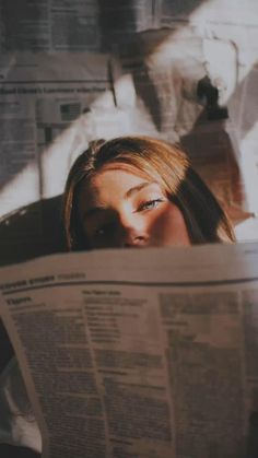 a woman reading a newspaper while laying in bed