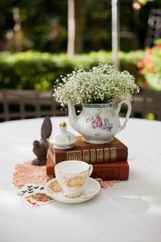 a tea cup and saucer sitting on top of a table next to a stack of books