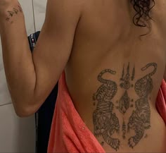 a woman with a tattoo on her back taking a selfie in the bathroom mirror